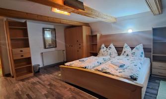 A modern bedroom with a double bed and two pillows. There are both shelves and a wooden wardrobe in the room.