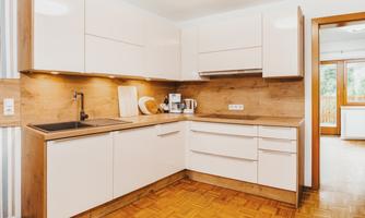 A modern kitchen with white cabinets and wood details. The equipment includes a sink, a countertop, and kitchen appliances.