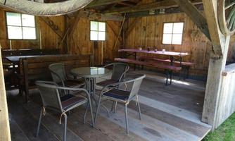 Interior view of a rustic cabin with wooden paneling. There are tables and chairs that invite relaxation.