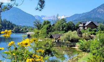 A picturesque lake surrounded by mountains and lush vegetation. Colorful flowers in the foreground add extra charm to the scene.