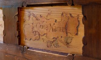 An artistically decorated wooden sign with an engraved inscription. It features a traditional design with floral motifs.