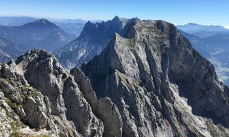 An impressive mountain landscape with rugged peaks and a clear blue sky. The rocks rise majestically into the height.