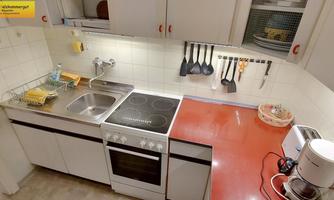Modern kitchen with white cabinets and a red countertop. The space is well equipped with a stove, sink, and kitchen appliances.