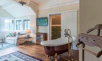 An elegant bathroom with a freestanding bathtub and a comfortable sofa. The large window front provides plenty of daylight and an inviting atmosphere.