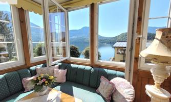 A cozy living area with a view of a lake and mountains. Large windows let in plenty of daylight and offer a beautiful view.