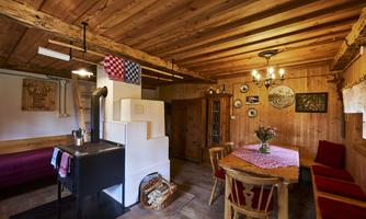 A cozy room with wooden interior, a dining table, and a fireplace. Various decorations hang on the walls.