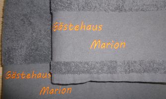 Gray towels with the inscription "Guest House Marion". The towels are neatly stacked.