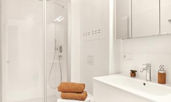 A modern bathroom with a shower and a sink. Towels and toiletries are neatly arranged.