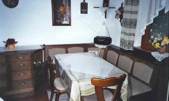 A cozy dining area with a table and chairs. Decorative elements hang on the wall and windows with curtains.