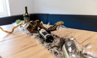 An elegant dining table with natural decor. Two wine bottles and glasses are placed on a decorative cloth.