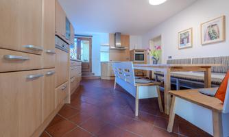 A modern kitchen with wooden furniture and a bright dining area. The room design is friendly and inviting.
