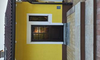 An entrance area with a yellow wall and a brown door. The stairs consist of light tiles and lead to the front door.
