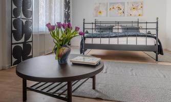 A modern bedroom with a black metal bed and a flower bench. A vase with fresh tulips sits on the table.