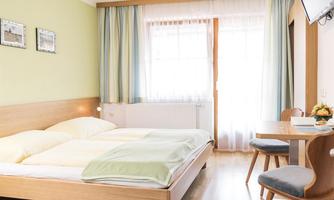 A bright and modern room with a double bed and a desk. The walls are decorated in soft colors, and a window provides plenty of daylight.