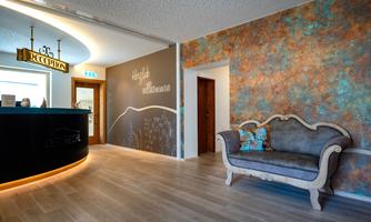 A modern reception area with an elegant reception desk and a stylish sofa. The wall is creatively designed and conveys an inviting atmosphere.