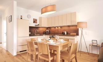 A modern kitchen with a dining area. The table is set for four people and the decor is bright and inviting.
