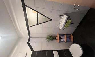 A modern bathroom with a sleek toilet and a sink. On the wall is a decorative mirror in the shape of an inverted V.