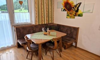 An inviting dining area with a wooden table and chairs. On the wall, there are pictures of a flower and a butterfly.