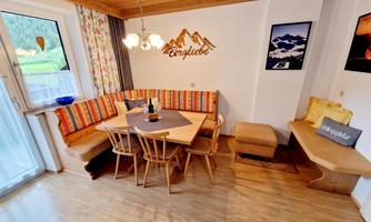 An inviting dining area with wooden decor and a cozy corner bench. The table is set for a small gathering, and the ambiance is warm and welcoming.