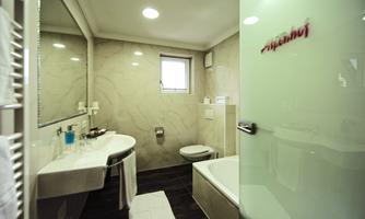 A modern bathroom with bright decor and elegant tiles. It features a bathtub, a sink, and a shower.