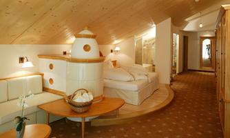 A cozy bedroom with bright wooden details and comfortable furniture. In the corner, there is a stylish fireplace and the room is well-lit.