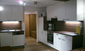 A modern kitchen with white cabinets and wooden details. It is well-equipped and has a bright, inviting atmosphere.