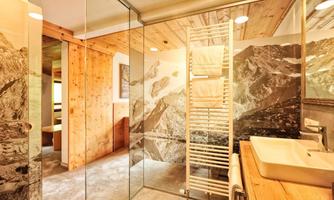 A modern bathroom with a glass shower cabin and wooden details. The walls feature an impressive mountain landscape.