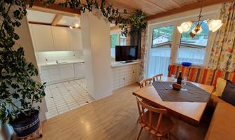 A cozy dining area with a wooden table and chairs. The open kitchen and large windows let in plenty of light.