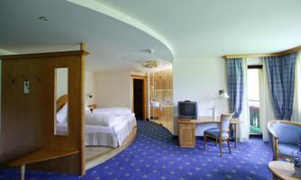 A modern hotel room with a double bed and a seating area. Large windows ensure plenty of daylight and a comfortable stay.