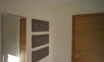 A bright hallway with a large mirror and hook racks on the wall. The door is made of wood and gives the room a warm ambiance.