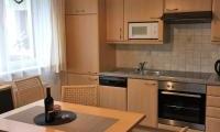 A modern kitchen with wooden cabinets and a dining table. The atmosphere is bright and inviting.