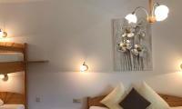 A cozy bedroom with a large double bed and a loft bed. The warm lights create an inviting atmosphere.