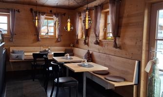 A cozy restaurant with wooden walls and large windows. The tables are simply but invitingly decorated.