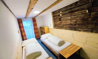 A simple room with two beds and modern wooden furniture.  
Large windows let in plenty of light and create a cozy atmosphere.