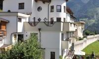 A modern accommodation surrounded by green meadows and mountains. The sky is clear and the view is picturesque.