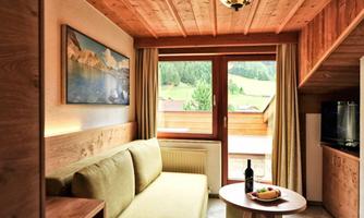 A cozy room with a green sofa and a small table. Large windows offer a beautiful view of the landscape.