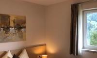 A cozy bedroom with a double bed and modern cushions. A window lets in daylight and offers a view of the outdoors.