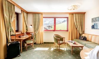 A comfortable hotel room with a view of the mountains. The decor is cozy and inviting, with a desk and a sofa.