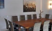 A modern meeting room with a large wooden table and stylish chairs. A decorative picture hangs on the wall, and the room is well-lit.