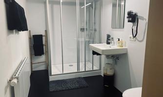 A modern bathroom with a glass shower and a sink. Black and white color scheme and well-organized toiletries.