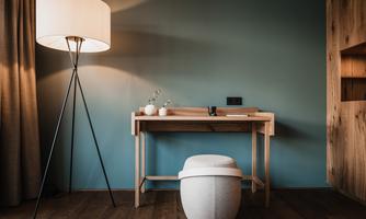A modern room with a decorative table and a lamp. The walls are painted in a soft blue, and the floor is wooden.