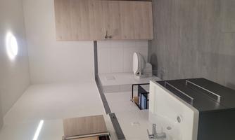 A modern bathroom with bright walls and gray floor. There is a sink, a toilet, and a wooden door.