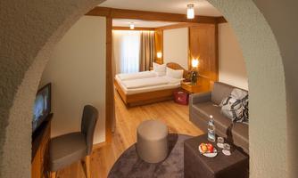 A comfortable room with a bed and a cozy seating area. Large windows let in plenty of light and create an inviting atmosphere.