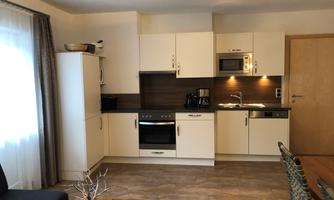 A modern kitchen with bright cabinets and stainless steel appliances. The room is well-lit and comfortably furnished.