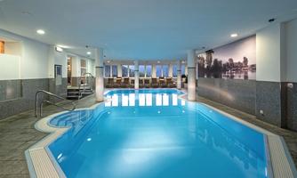 An elegant indoor pool with clear water and comfortable loungers. The walls are brightly and modernly designed, creating a relaxing atmosphere.