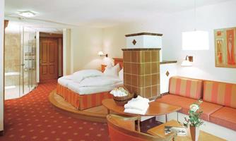A spacious hotel room with a comfortable bed and a sitting area. The warm colors and modern decor create an inviting atmosphere.