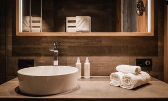A modern bathroom with an elegant sink and soft towels. The warm wood and stone elements create an inviting atmosphere.