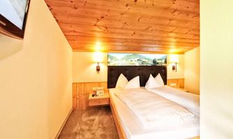 A cozy bedroom with a double bed and wooden walls. Soft lighting creates a relaxed atmosphere.