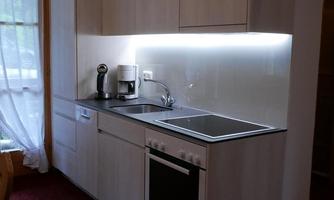 A modern kitchen with light wood cabinets and an elegant workspace. The kitchen is well-lit and equipped with all necessary appliances.