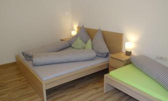 A bedroom with two beds and a stylish wood design. The pillows are striped, and there is soft lighting from bedside tables.